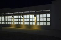 an empty building with two large windows next to it is dimly lit in the dark