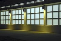 an empty building with two large windows next to it is dimly lit in the dark