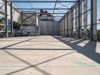 an industrial warehouse on a sunny day with sun casting shadows on the cement ground and walls