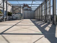 an industrial warehouse on a sunny day with sun casting shadows on the cement ground and walls