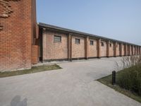 there is a long brick building with several windows, and a signpost on the corner