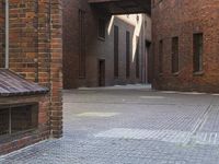 a view through an alleyway looking towards a building with brick structures and windows in it