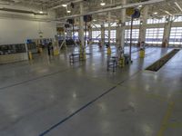 a large warehouse building with a metal and plastic flooring area and several workers working on equipment