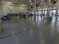 a large warehouse building with a metal and plastic flooring area and several workers working on equipment