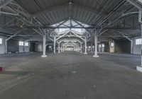 a large empty industrial warehouse with many windows and floors and large ceiling area, concrete floors and ceiling structure