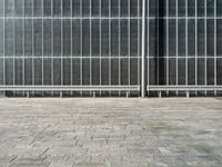 the sidewalk is lined with grey tile bricks and cement squares and a black wall behind