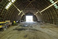 two large grain bins sit in the center of a field, surrounded by silos