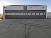 the industrial warehouse is painted gray and white and there are tires on the pavement to indicate where the space is going