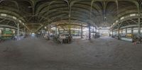 a fisheye lens image of the inside of a large building with various people, some tables and some buildings with arches