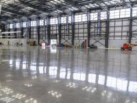 a small airplane on display inside of a building with big windows and other objects around