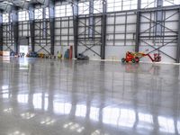 a small airplane on display inside of a building with big windows and other objects around