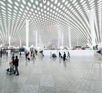 a large open building with people walking around it at the airport with luggage bags on the ground