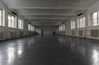 this is a long corridor in a building with many windows on the sides and light colored floors