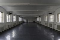 this is a long corridor in a building with many windows on the sides and light colored floors