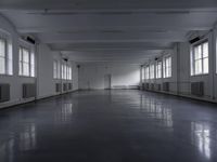 a large hallway that has all windows, and no light in it, on the floor