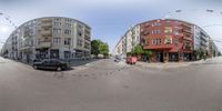 view of an intersection with traffic, buildings and people on it in 360 - ball