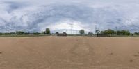 a view of an empty baseball field under a cloudy sky in a panoramic lens