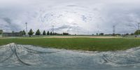 a ballpark with a lot of green grass and white clouds in the sky around it