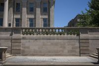 two concrete pillars line the wall on the outside side of a building with a large, stone balcony