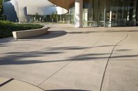 the large modern building is built out of concrete and features an entrance on one side, walkway on the other, and glass - covered in