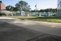 an empty sidewalk and grass in front of a building that has fenced in on the sides of it