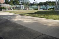 an empty sidewalk and grass in front of a building that has fenced in on the sides of it