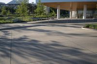a large building that is outside in the sunlight on a sunny day and a little boy on a skate board is standing beside him