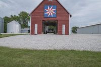 an open garage sitting in front of a barn next to two other buildings, each with one on the second floor