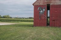 the old, weathered building has been painted with graffiti and is in a field with corn