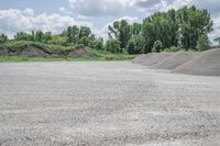 gravel that is stacked in the middle of a parking lot next to trees in the background