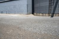 a big industrial silos in a parking lot with gravel around it and an open door to the outside