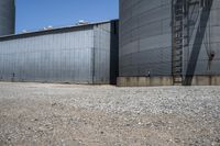 a big industrial silos in a parking lot with gravel around it and an open door to the outside