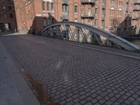 a bridge crossing a street by a city street on a cloudy day by itself, with parked bicycles underneath it