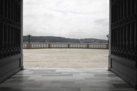 the view out of an open door of a patio with railings and stone floor