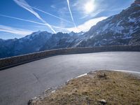 a mountain side with a curve road and sky in the background as viewed from below