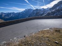 a mountain side with a curve road and sky in the background as viewed from below