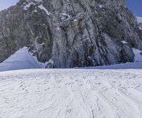 a person skiing down a steep mountain next to snow covered rocks and large rocks on the ground