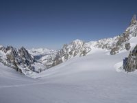 skiers are skiing on the snow with mountains in the background under a clear blue sky