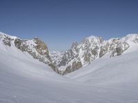 skiers are skiing on the snow with mountains in the background under a clear blue sky