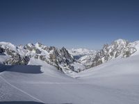 skiers are skiing on the snow with mountains in the background under a clear blue sky