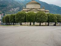 people walk through a park area with a hill in the background behind them and two benches on each side of the plaza