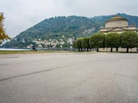 people walk through a park area with a hill in the background behind them and two benches on each side of the plaza
