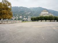 people walk through a park area with a hill in the background behind them and two benches on each side of the plaza