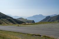 a lone road in the mountains of europe, with mountains beyond it and the road is wide enough