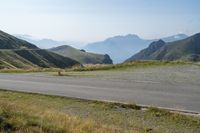 a lone road in the mountains of europe, with mountains beyond it and the road is wide enough