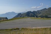 a lone road in the mountains of europe, with mountains beyond it and the road is wide enough