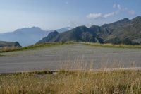 a lone road in the mountains of europe, with mountains beyond it and the road is wide enough