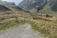 a motorcycle parked on a small mountain side road near mountains with no cars driving on it