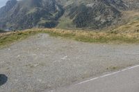 a motorcycle parked on a small mountain side road near mountains with no cars driving on it