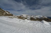 a snowy mountain with a person skiing over it on the snow covered slope looking towards the mountains